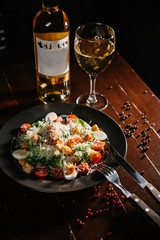 Fresh caesar salad in white plate on dark wooden table. Top view copy space.