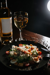 Fresh caesar salad in white plate on dark wooden table. Top view copy space.