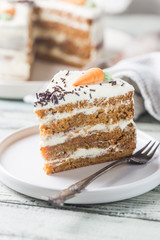 Healthy homemade carrot cake with cream cheese frosting on white wooden table