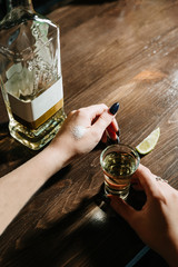 hand with tequila shots on wooden tabletop