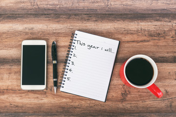 New Year's Resolutions Concept - Smartphone, pen and cup of coffee background.