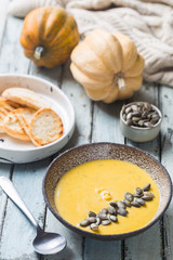 Seasonal autumn food. Healthy Pumpkin soup with cream and organic pumpkin seeds.