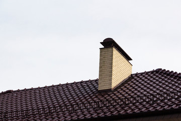Chimney pipe of brick on the roof of the house.