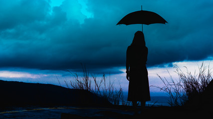silhouette woman standing with an umbrella to prevent rain on a rainy day