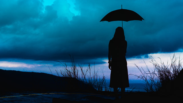 silhouette woman standing with an umbrella to prevent rain on a rainy day - Powered by Adobe