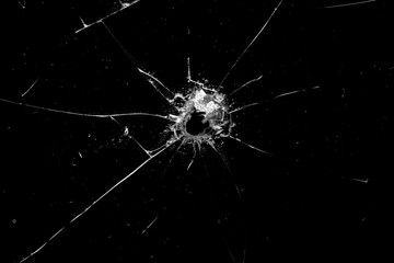 hole in the glass with cracks isolated on a black background