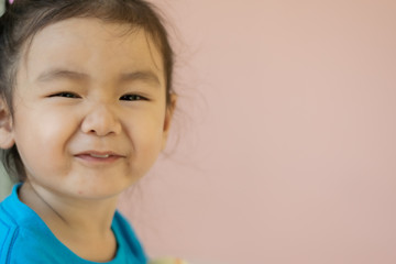 Kindergarten Asian girls wearing blue shirts, sitting, smiling.