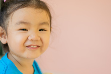 Kindergarten Asian girls wearing blue shirts, sitting, smiling.
