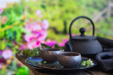 Two cups of green tea and teapot on wooden table and nature background with copy space