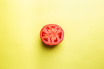 Tomato slice isolated on yellow background, top view