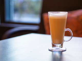 Long glass cup of cappuccino on a wooden table with copy space for cafe banner promo text