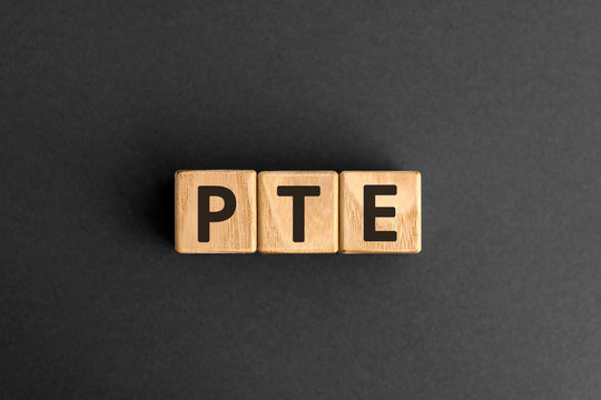PTE - acronym from wooden blocks with letters, Pearson Tests of English PTE concept Foreign Language exams,  top view on grey background