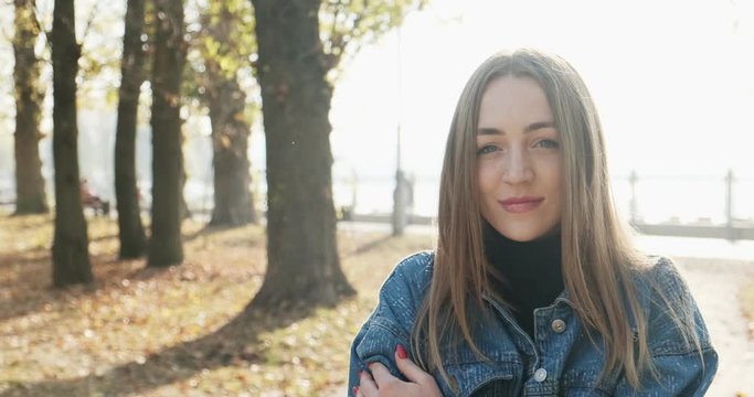 Young happy smilling girl walking in the autumn park. Young atractive woman walks and smile in the sun rays