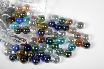 Colored glass bullets out of glass bowl on white ground-