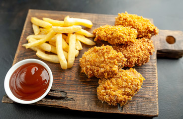 fried chicken with french fries and food nuggets - on stone background