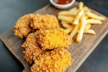 fried chicken with french fries and food nuggets - on stone background
