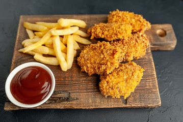 fried chicken with fries and slices of food - on a stone background with copy space for your text