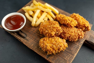 fried chicken with french fries and food nuggets - on stone background