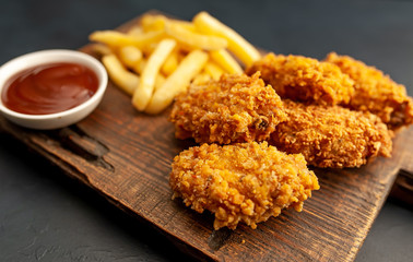 fried chicken with french fries and food nuggets - on stone background