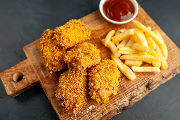 fried chicken with french fries and food nuggets - on stone background