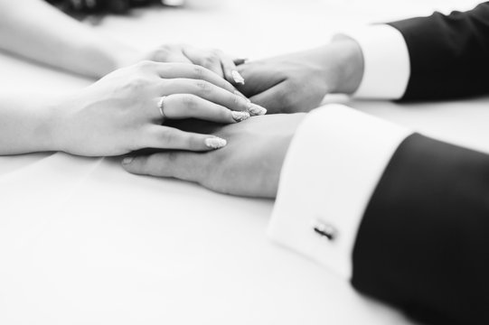 picture of man and woman holding hands. Wedding ceremony. Groom and bride. Wife and husband. Black and white photo. Closeup.