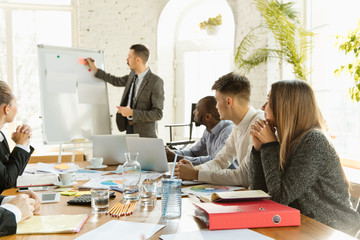 Group of young business professionals having a meeting. Diverse group of coworkers discuss new decisions, future plans and strategy. Creative meeting and workplace, business, finance, teamwork.