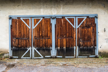 Old shabby locked wooden garage doors. Blue metal frame.