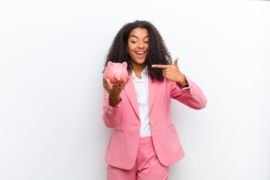 Young Pretty Black Woman With A Piggy Bank Against White Wall