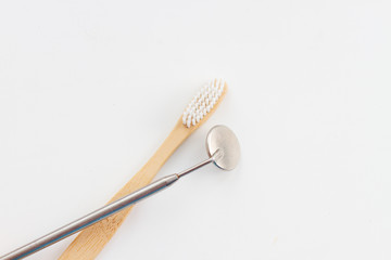 dental mirror and bamboo toothbrush on a white background