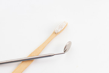 dental mirror and bamboo toothbrush on white background