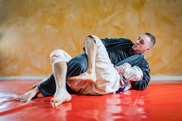 Two brazilian jiu jitsu athletes working on BJJ guard position at the training sparring or drilling fighters at the academy class