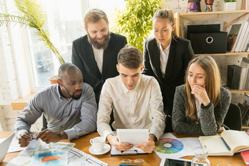 Group of young business professionals having a meeting. Diverse group of coworkers discuss new decisions, future plans and strategy. Creative meeting and workplace, business, finance, teamwork.