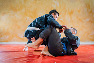 Two brazilian jiu jitsu athletes working on BJJ guard position at the training sparring or drilling...