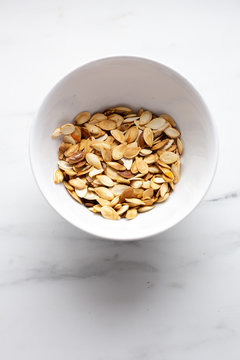 roast Pumpkin seeds in white bowl on marble background with copy space