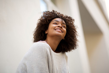Close up happy african american woman with curly hair smiling outside