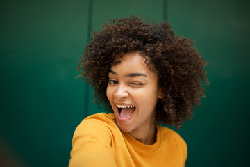 happy african american young woman taking selfie with winking eye