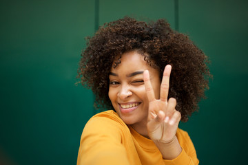 smiling african american young woman taking selfie with peace hand sign