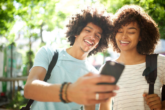 Happy Young African American Couple Standing Outside Looking At Cellphone