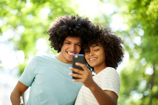 happy afro guy taking selfie with smiling young african american woman