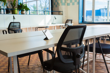 Loft style office with white brick walls and concrete columns. There is a meeting area with a large white table with black chairs