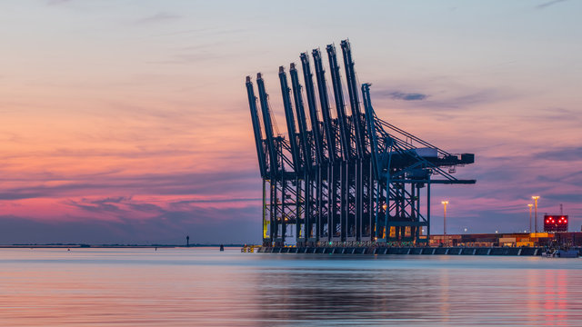 Row of container terminal cranes at red colored sunset in Port of Antwerp, Belgium