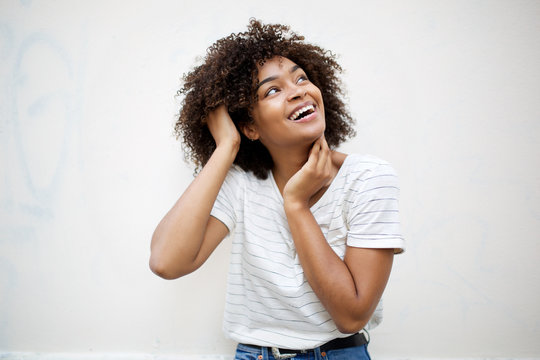 cheerful young african american woman laughing and looking up by white background