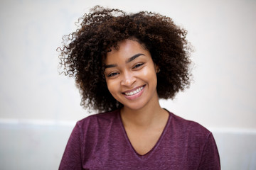 front horizontal portrait of happy young african american woman with curly hair by white wall