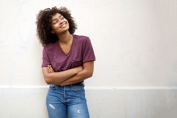 cool african american girl smiling with arms crossed by white background
