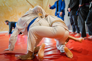 Fototapeta na wymiar Brazilian jiu jitsu BJJ fighters working on the takedown or judo techniques at the training at academy wearing white kimono gi