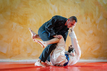 Two brazilian jiu jitsu athletes working on BJJ guard position at the training sparring or drilling...