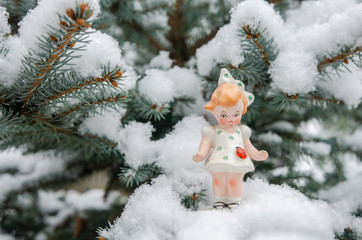 Porcelain figurine doll in the snow covered pine tree - girl afraid of the ladybug climbing her dress