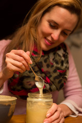 Obraz na płótnie Canvas Eine junge Frau löffelt Honig aus einem Glas