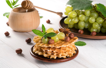 waffles with honey and grapes on a wooden background