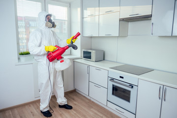 white worker spraying pesticide on induction hob